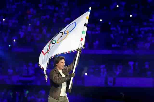 Tom Cruise makes a dramatic entrance, abseiling into the Stade de France to collect the Olympic flag.




